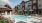 swimming pool in a courtyard with umbrellas and lounge chairs